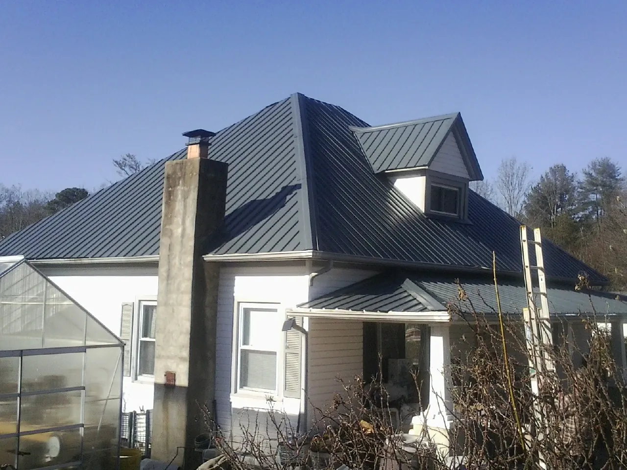 Dark blue standing seam metal roof on a white farmhouse with dormer — Slate & Tile Roof Repair by Roofing Brothers in White City