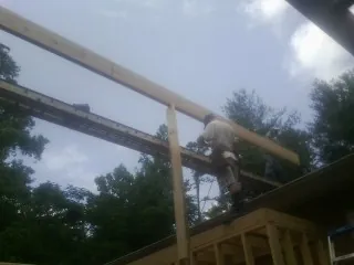 Carpenter setting a ridge beam over a new addition frame — Ice Dam Removal by Roofing Brothers in White City