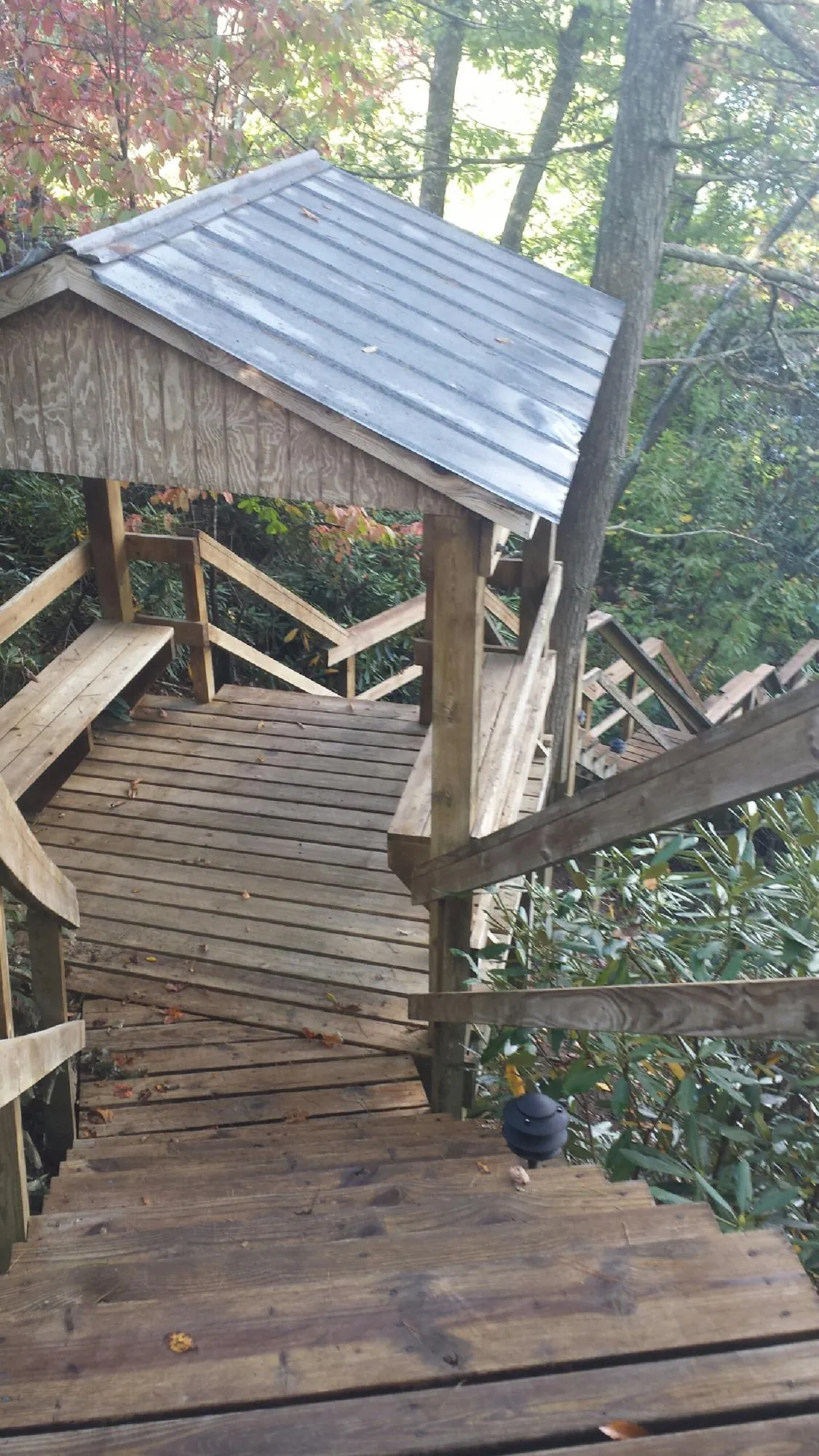 Metal roofed shelter over wooden steps on a wooded walkway — Skylight Repair & Installation work by our crew in White City