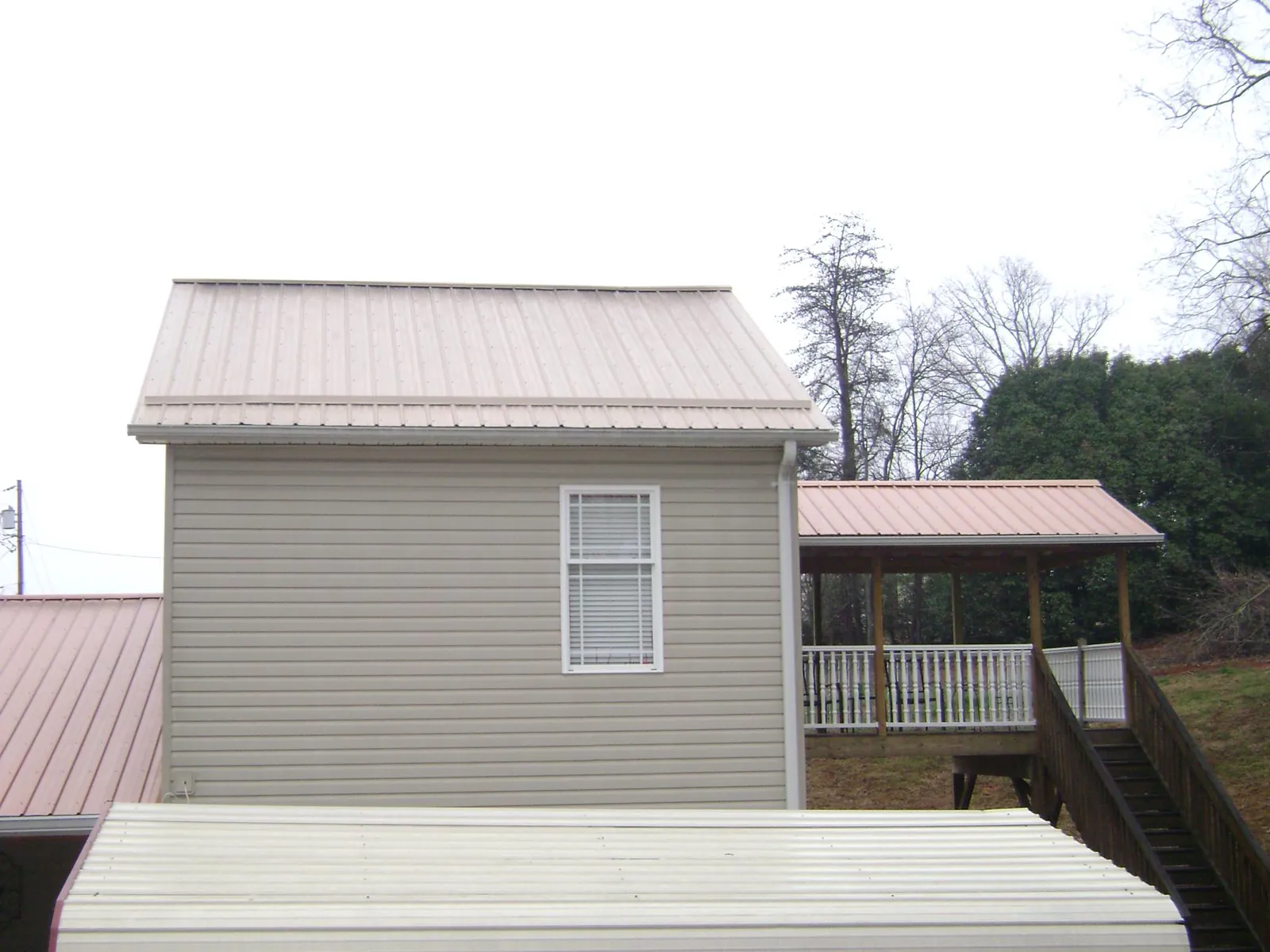 Tan metal roofs on a two story addition and attached porch, from a Roof Replacement job in White City