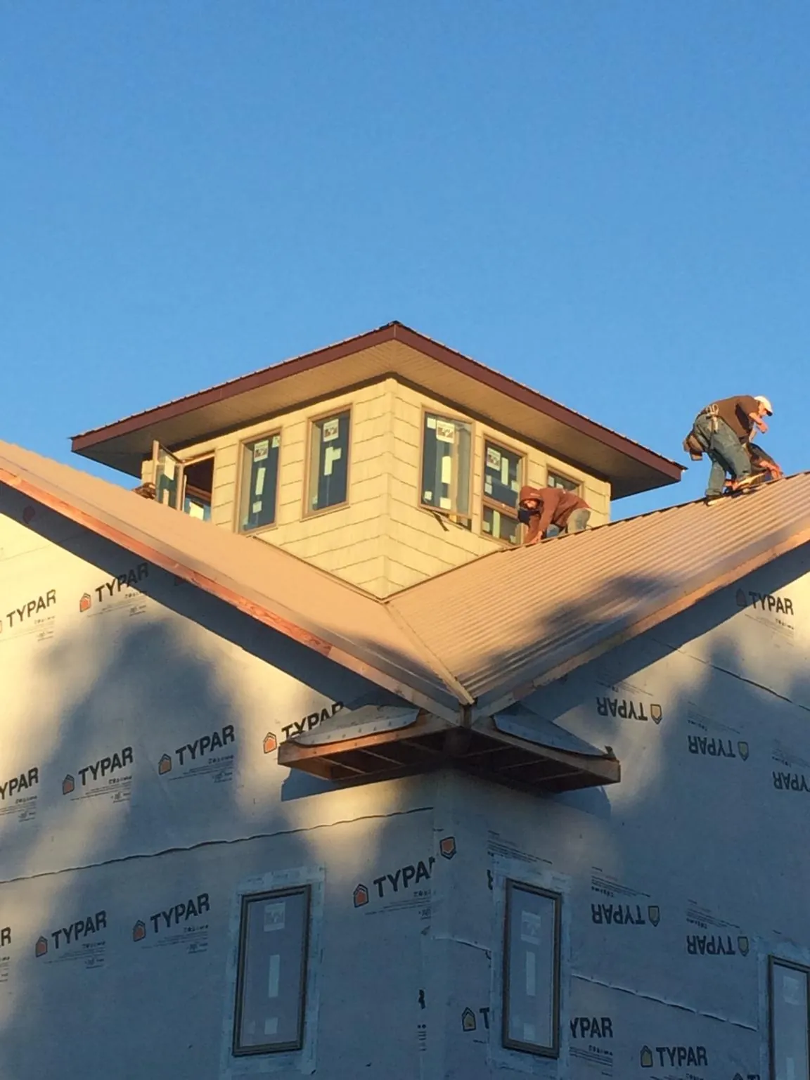 Roofers working around a rooftop cupola on a new metal roof at sunset — Roof Waterproofing in White City by Roofing Brothers